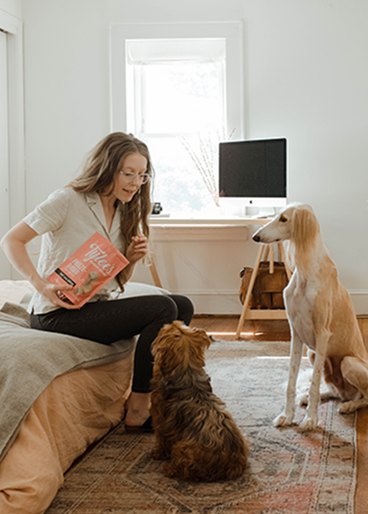 Woman feeding a dog from a bag of treats